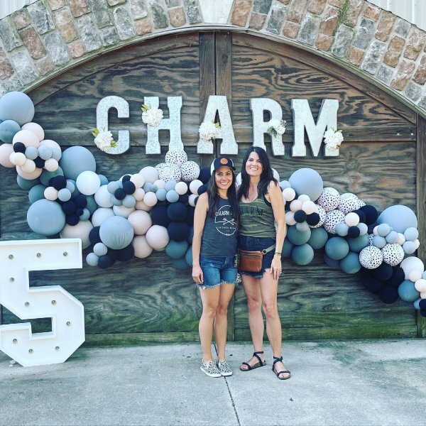 Two women posing in front of Charm background with ballons